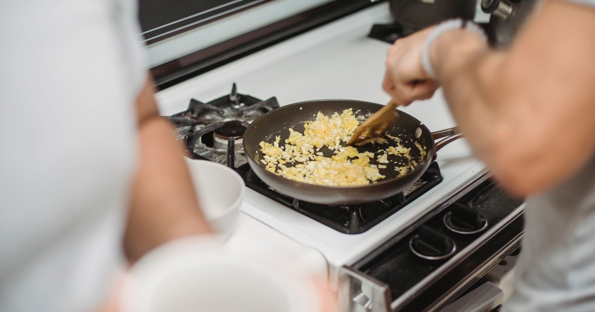 Close-up of a person cooking scrambled eggs on a stovetop, highlighting a cozy kitchen setting.