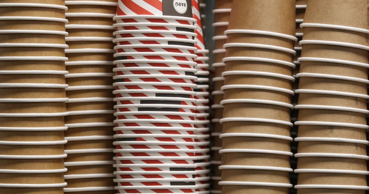 Close-up of paper coffee cups with red striped design and plain brown cups stacked together.