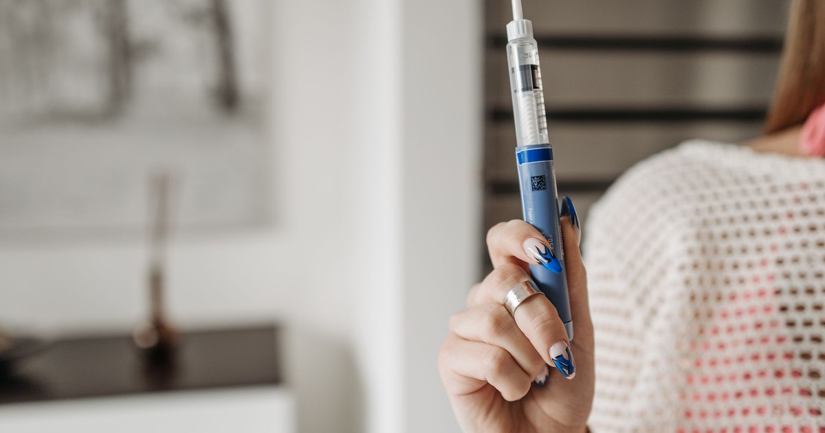 Woman holding an insulin pen, showcasing healthcare and diabetes management in a modern setting.