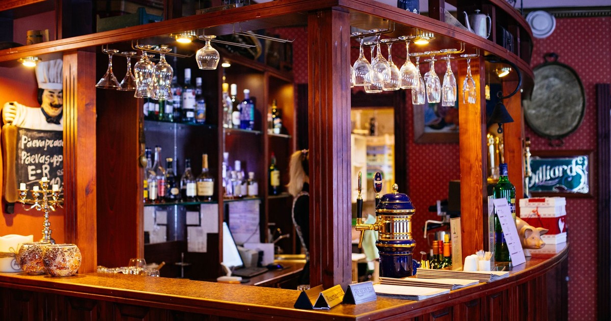 Warm and inviting pub interior featuring a wooden bar and hanging wine glasses.