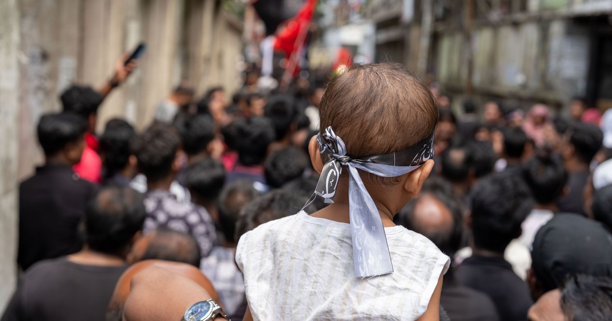 A child in a crowd, observing a street procession, showcasing cultural gathering.