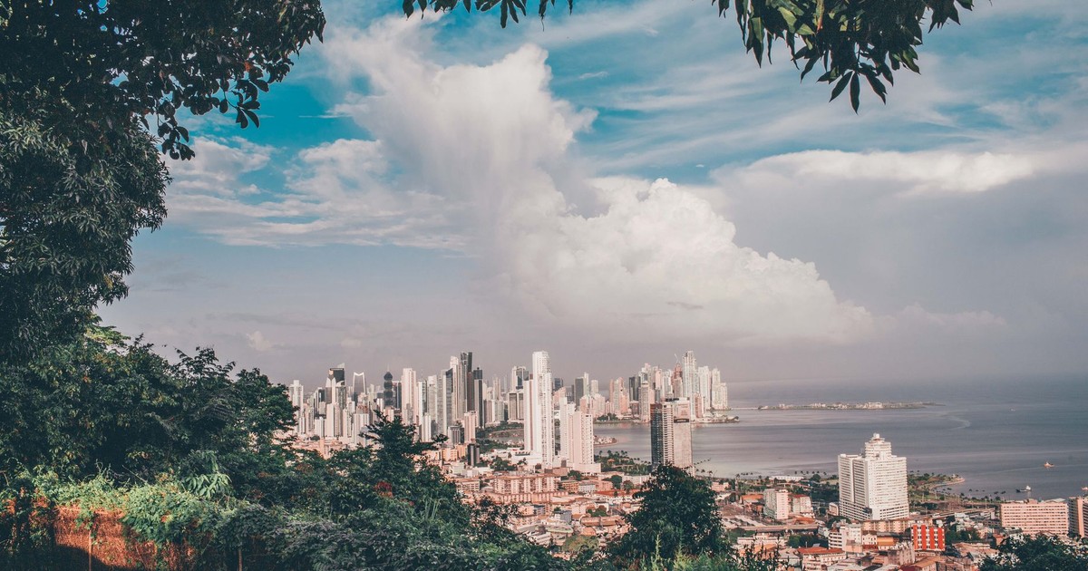 Scenic view of Panama City skyline under a vibrant sky with lush green foreground.