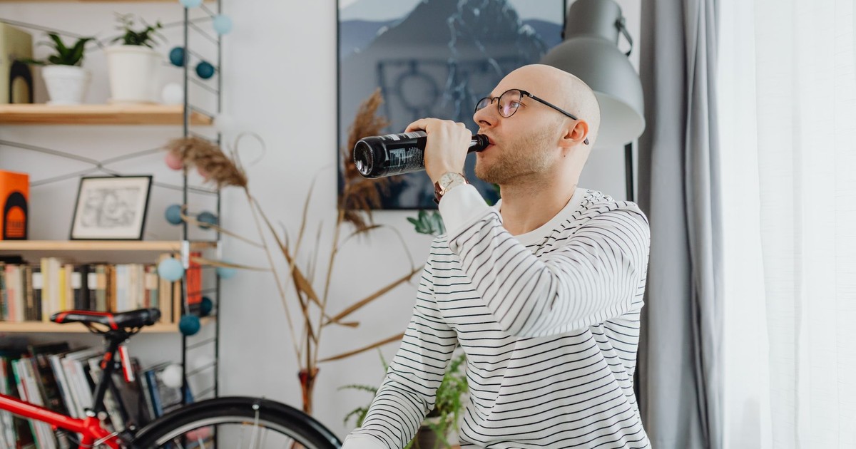 Bald man relaxing and drinking a beverage in a cozy living room.