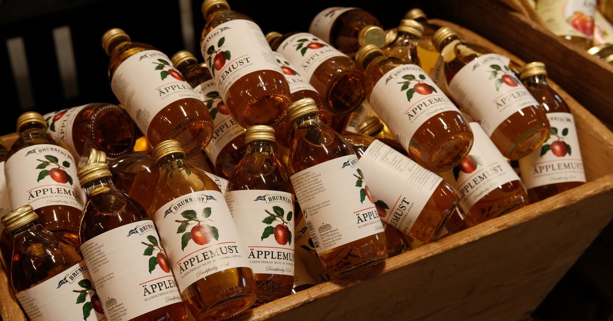 A variety of bottled apple juice arranged in a wooden crate, perfect for market displays.