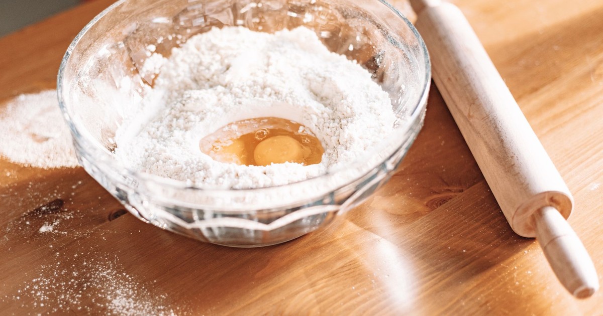 Mixing flour and eggs for baking on a wooden table.