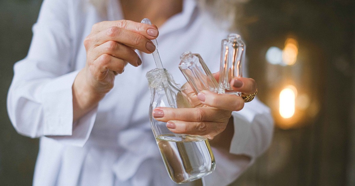Close-up of a woman using a dropper with glass bottles, capturing the essence of beauty products and skincare rituals.