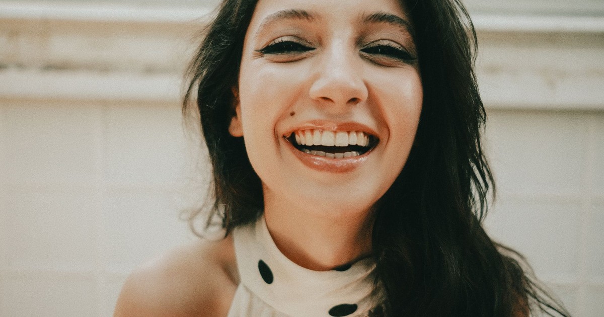 Young woman with a joyful expression and bright smile indoors. Close-up portrait.