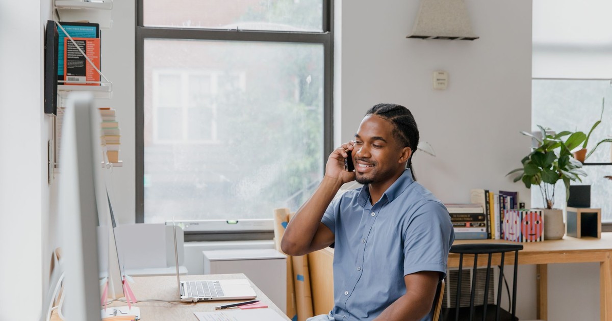 Adult man engaged in office work, speaking on phone, showcasing a professional environment.