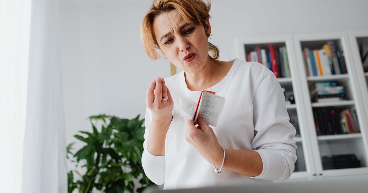 A concerned woman reviews her finances while holding receipts, showing a worried expression.