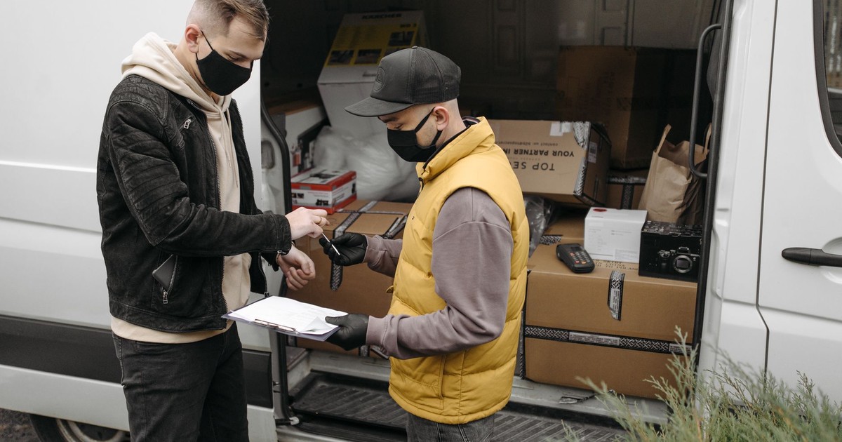 Courier wearing face mask delivers packages to a customer maintaining safety protocols.