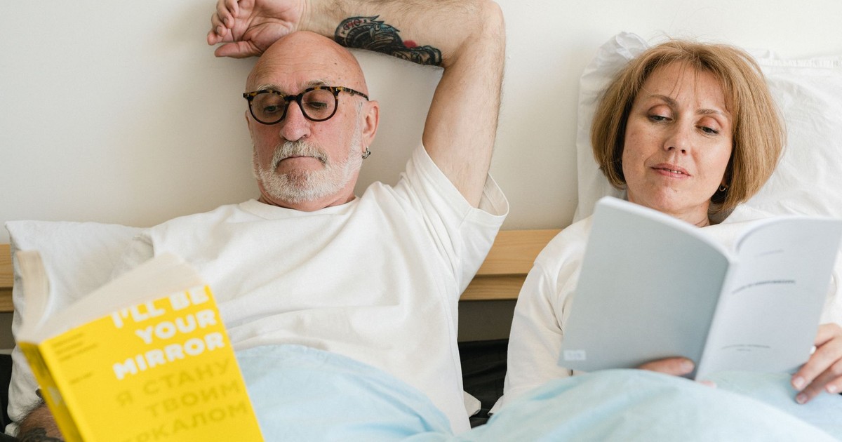 Senior couple reading together in bed, sharing a moment of relaxation and connection.
