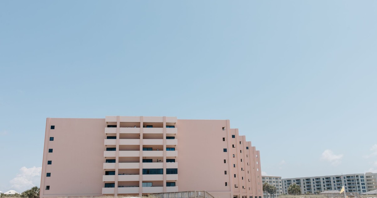 Modern beachfront apartment building with clear sky and beach umbrellas.