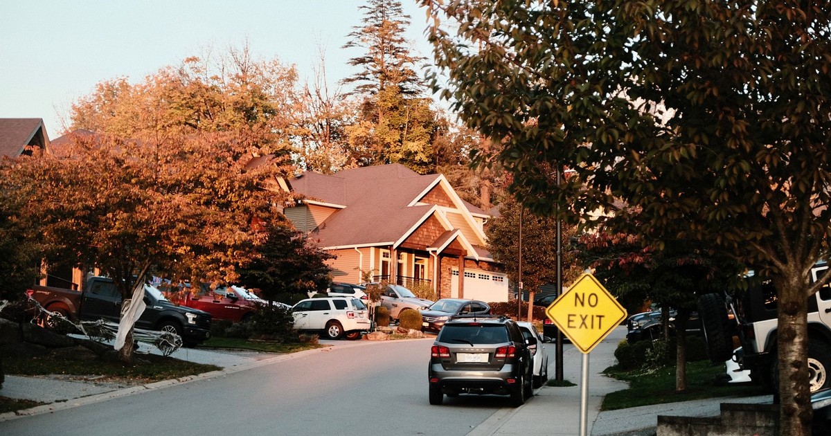 Charming suburban street scene with houses, cars, and a no exit sign in fall.