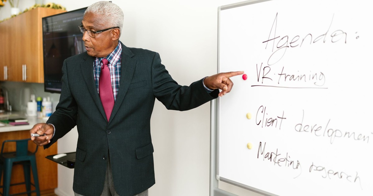 Senior African American businessman presenting VR training agenda during office meeting.
