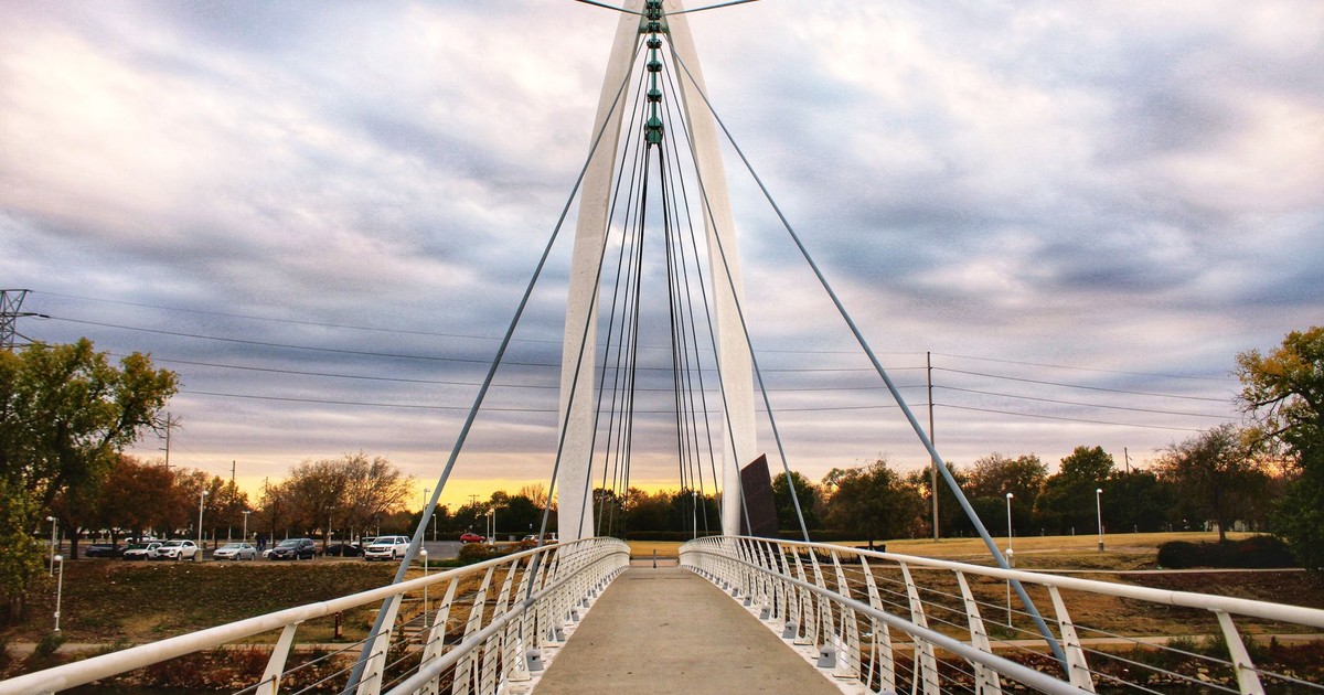 A stunning view of a suspension bridge in Wichita, KS, during sunset, showcasing architectural beauty.