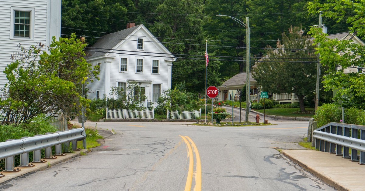 Tranquil intersection scene with classic white houses and lush greenery.