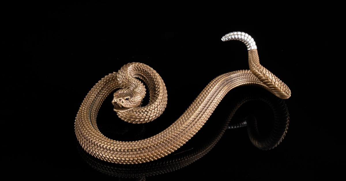 Stunning close-up of a bronze snake sculpture with intricate detailing on a black background.