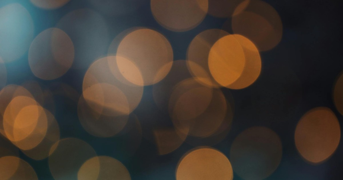 Abstract bokeh background with warm orange circles on a dark backdrop.