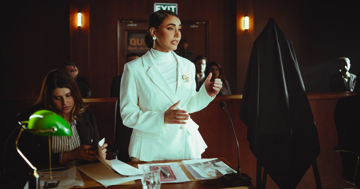 Confident woman in white suit presenting a case in an elegant courtroom setting.