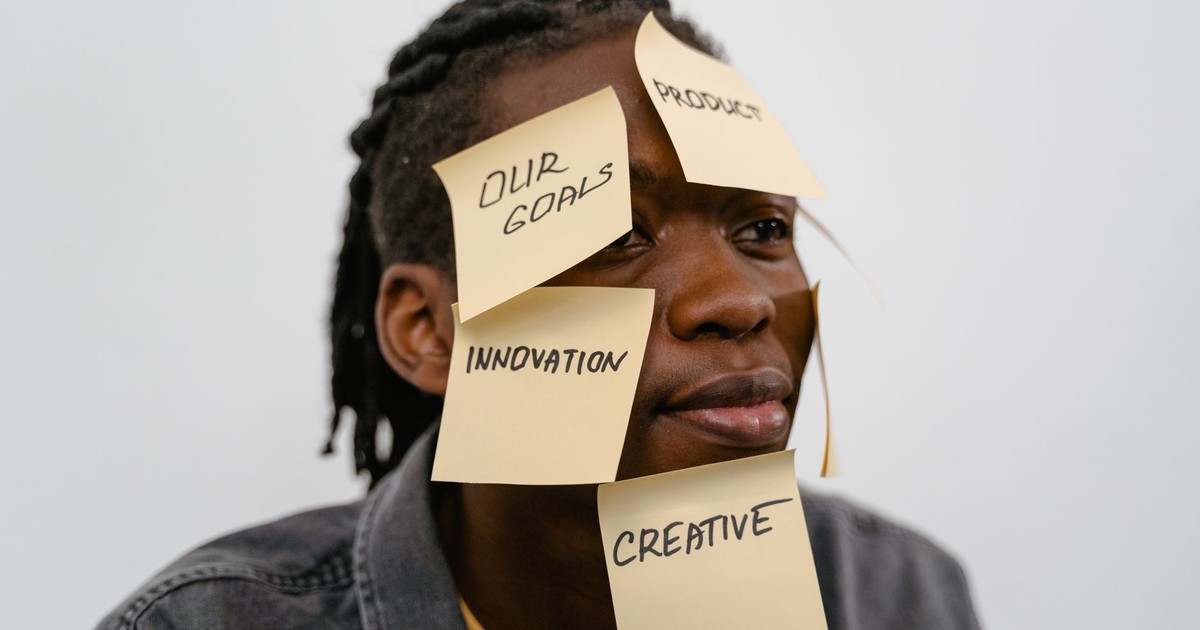 A creative adult with sticky notes displaying innovation concepts on their face.