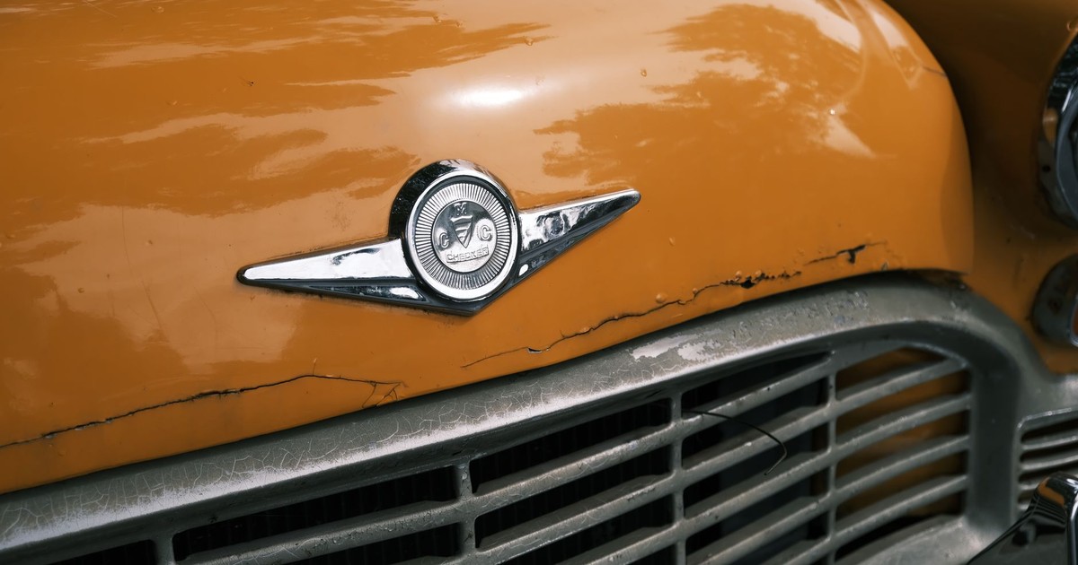 Detailed view of a classic vintage yellow taxi front emblem and grill.