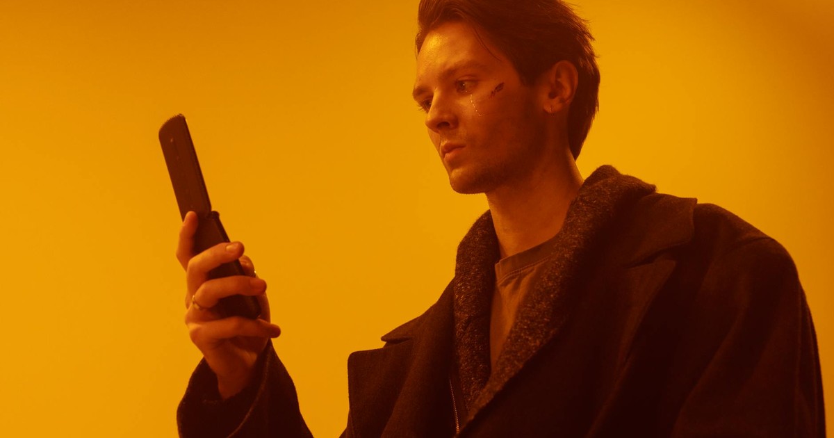 Dramatic studio portrait of a man using a vintage flip phone.
