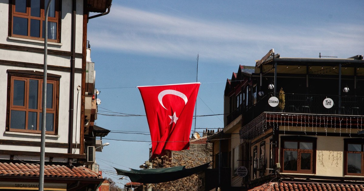 A vibrant Turkish flag hanging between traditional buildings in Konya, Türkiye.