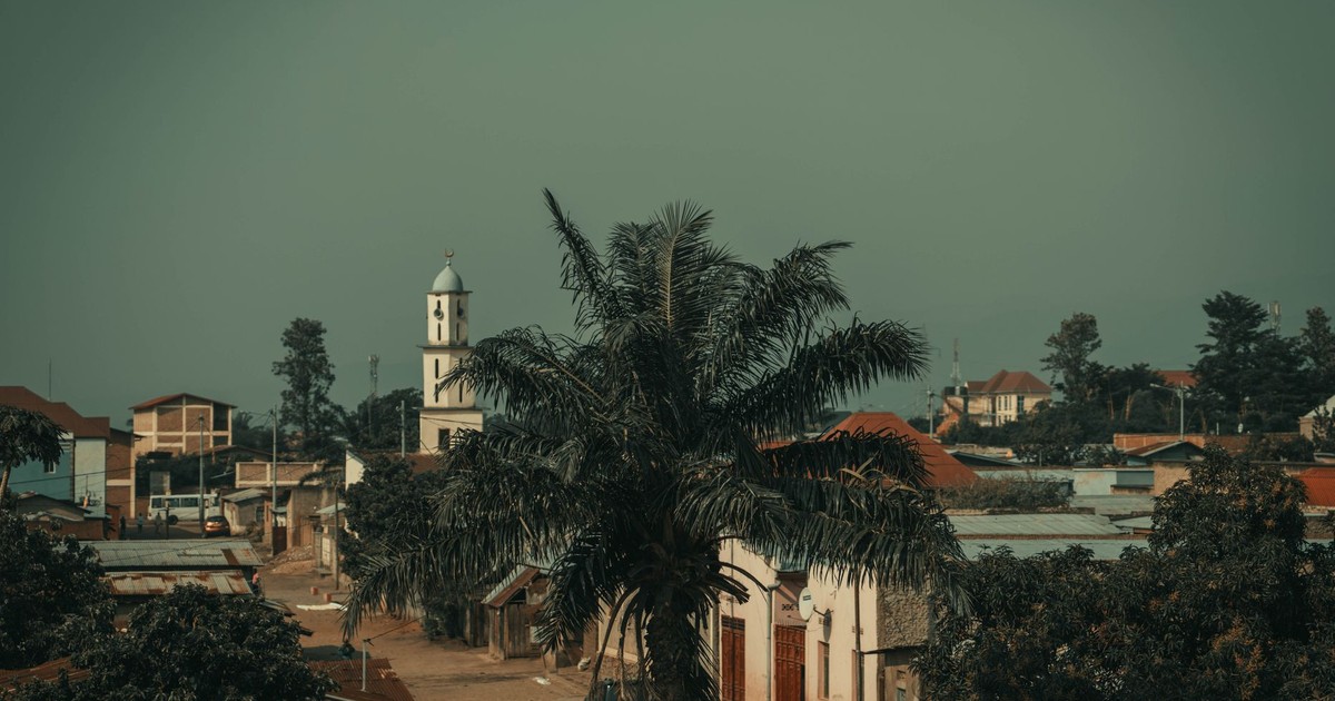 Scenic view of Bujumbura cityscape featuring a prominent church tower and palm tree.