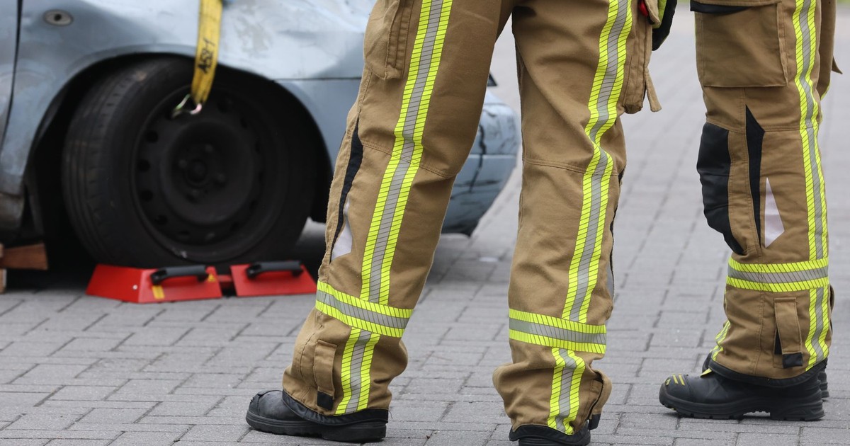 Firefighters inspecting a car accident wearing protective gear. Focus on pants and footwear.