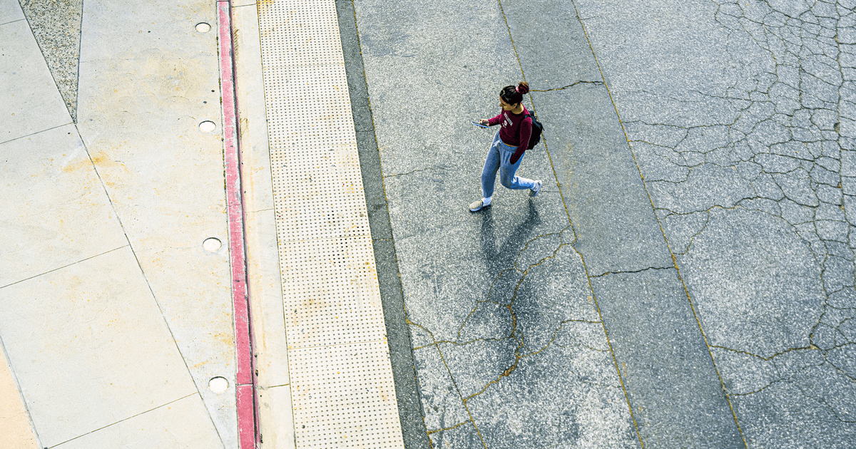 Aerial view of a woman walking on city pavement, captured from above.