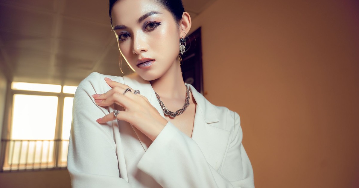 A fashionable woman posing elegantly indoors, showcasing jewelry and style.