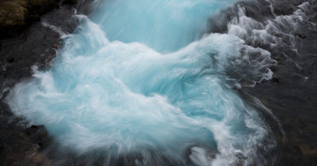 A mesmerizing shot capturing the vibrant turquoise flow of a river cascading over rocks.