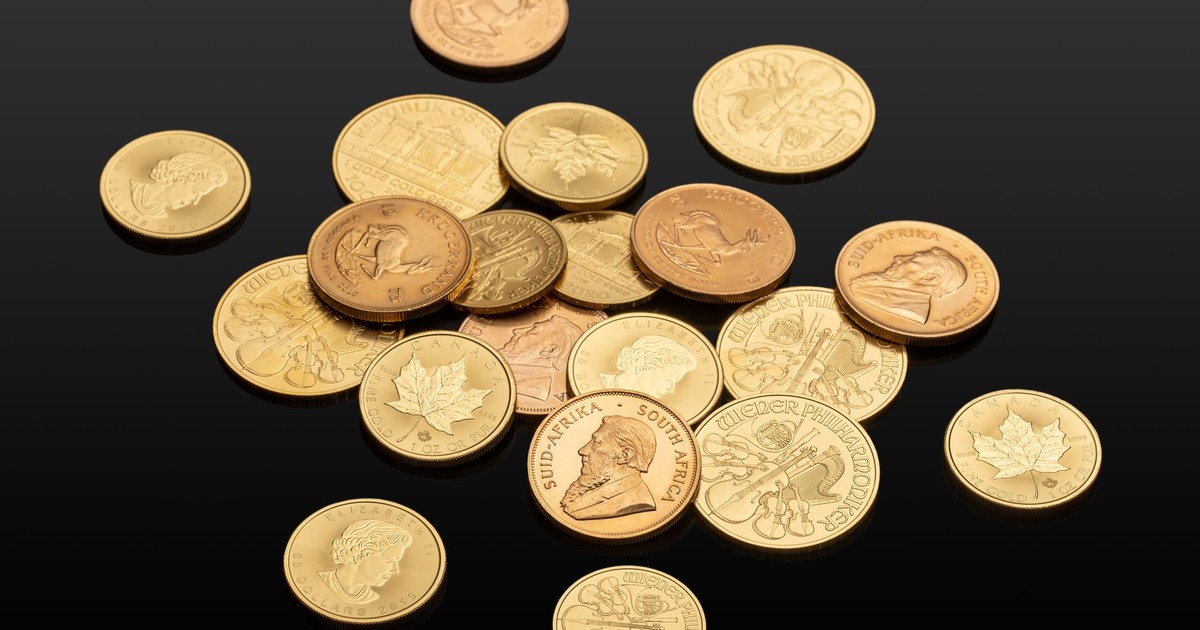 Close-up of various international gold coins on a reflective black surface, showcasing global currency.