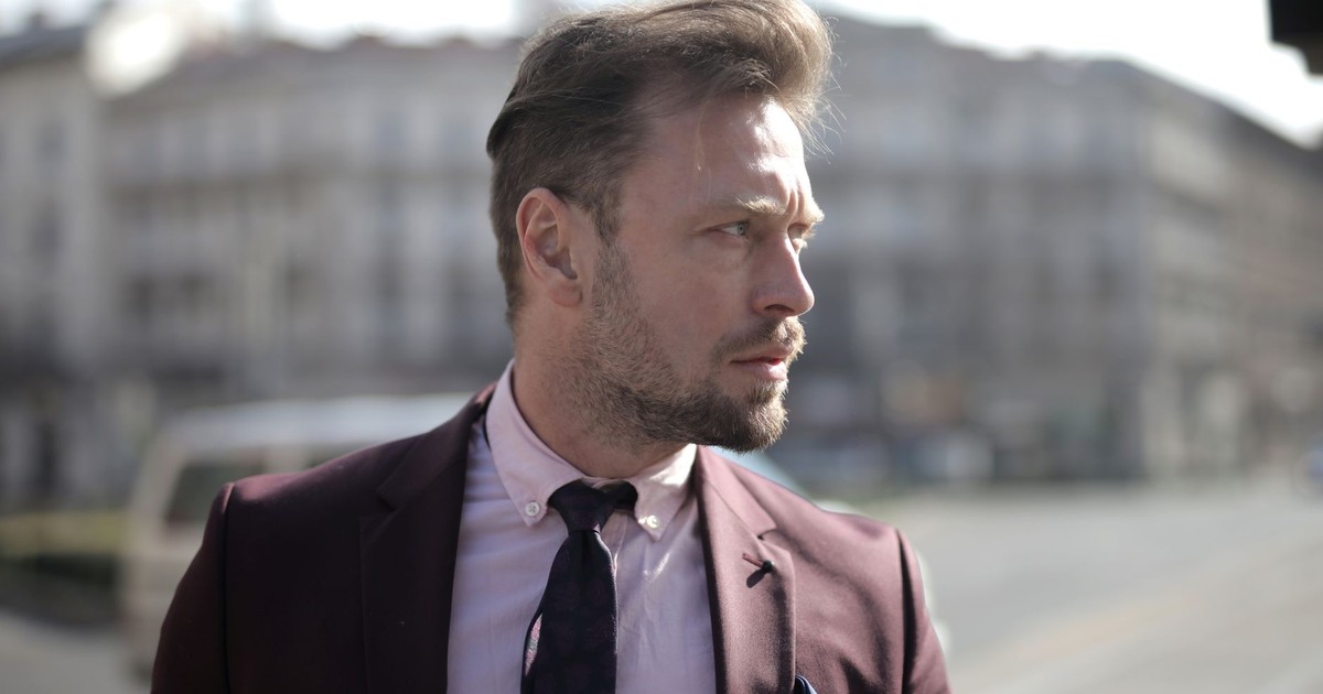 Professional man in suit on city street, looking pensive under daylight.