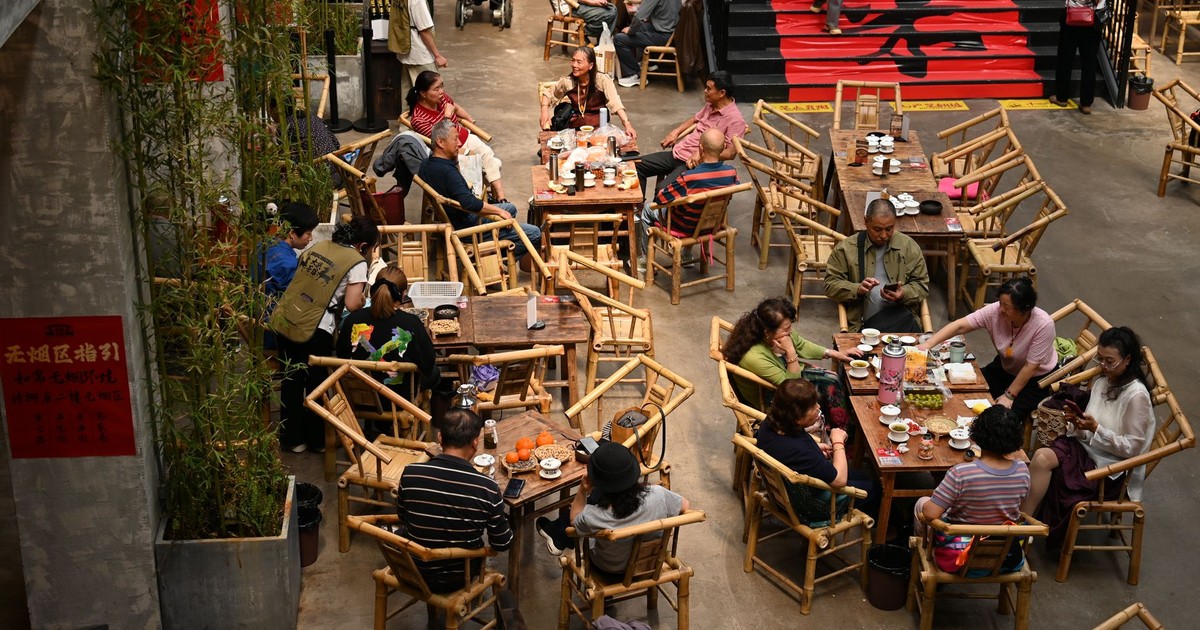 Overhead view of an indoor café with patrons seated at bamboo tables, capturing lively discussions.