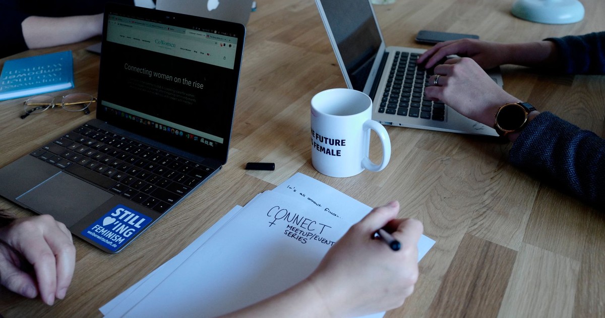 Team working with laptops and notes during a meeting at a wooden table.