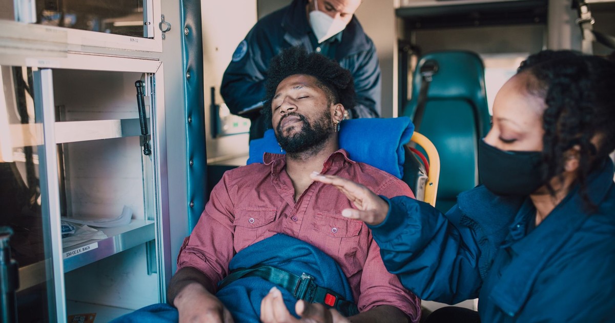 Paramedics provide urgent care to an injured man inside an ambulance.