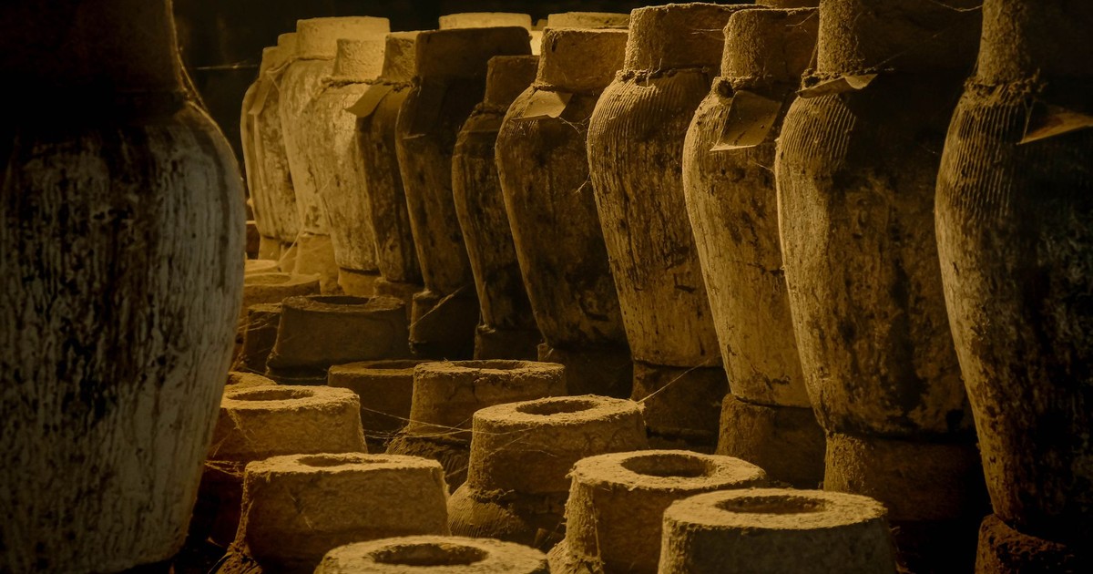 A collection of ancient clay amphorae displayed in a dimly lit warehouse, evoking historical ambiance.