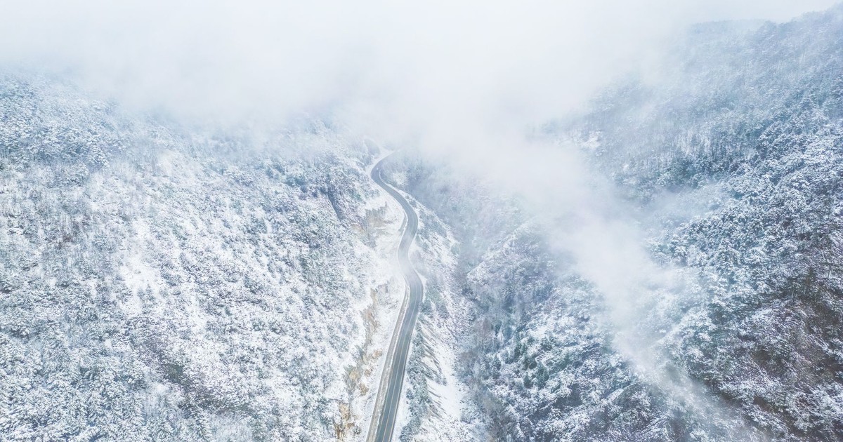 Majestic aerial view of a winding road through snow-covered mountains.