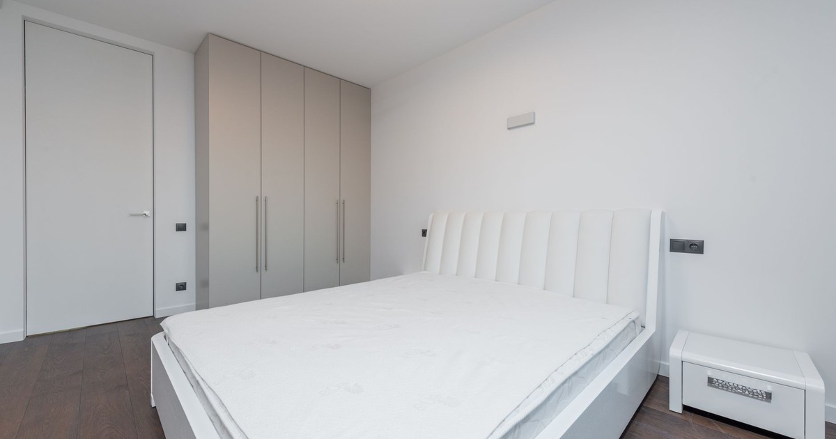 Bright minimalist bedroom featuring a white bed and contemporary design.
