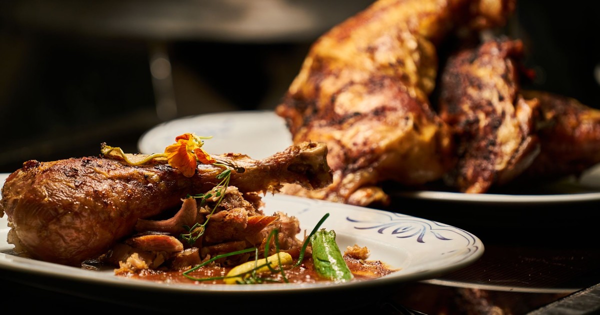 Close-up of a deliciously roasted chicken dish served with garnish, highlighting fine cuisine.