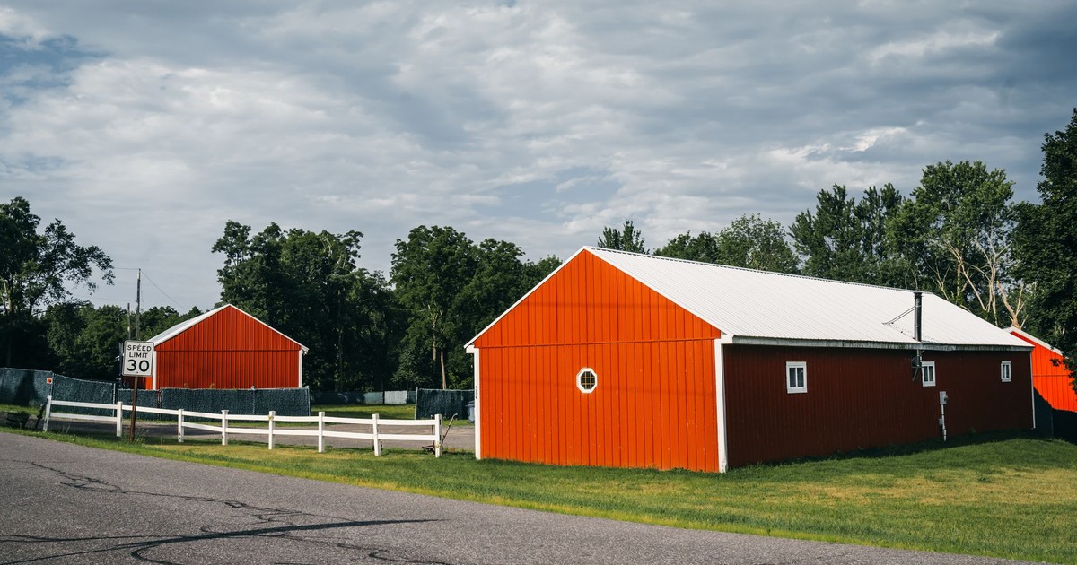Charming red barns alongside a country road under a cloudy sky in Jersey City.