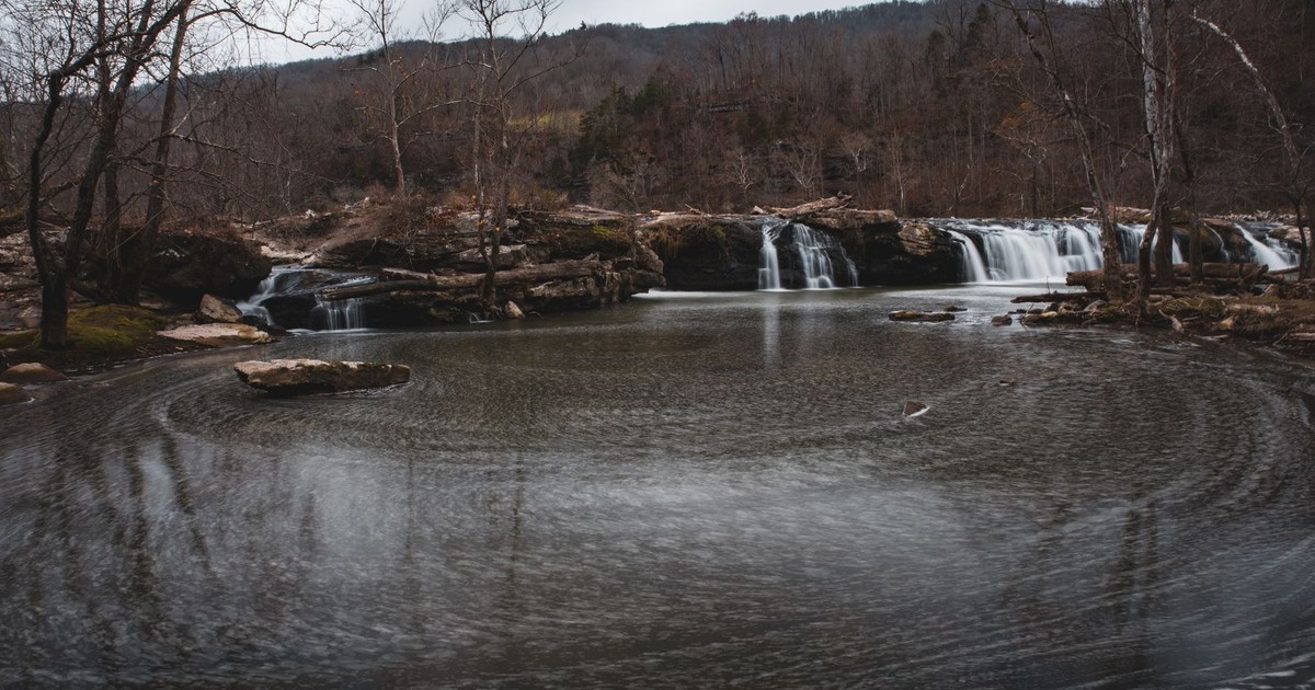 Serene view of Sandstone Falls surrounded by bare trees in West Virginia's natural landscape.