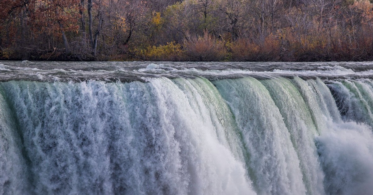 Stunning autumn scene of Niagara Falls with vibrant foliage in the background.