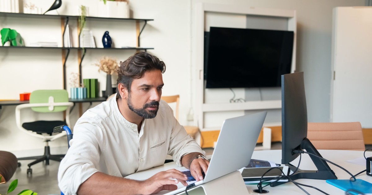 Professional man using a laptop in a modern office setting, showcasing accessibility and business environment.