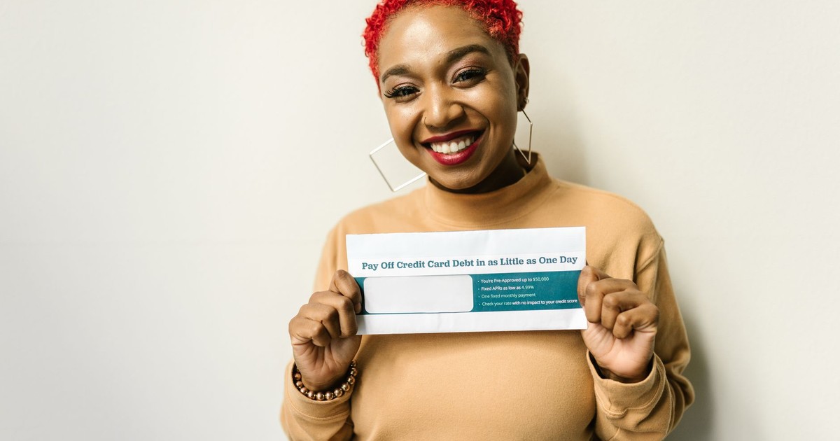 Happy woman with red hair holding an envelope for debt payoff.