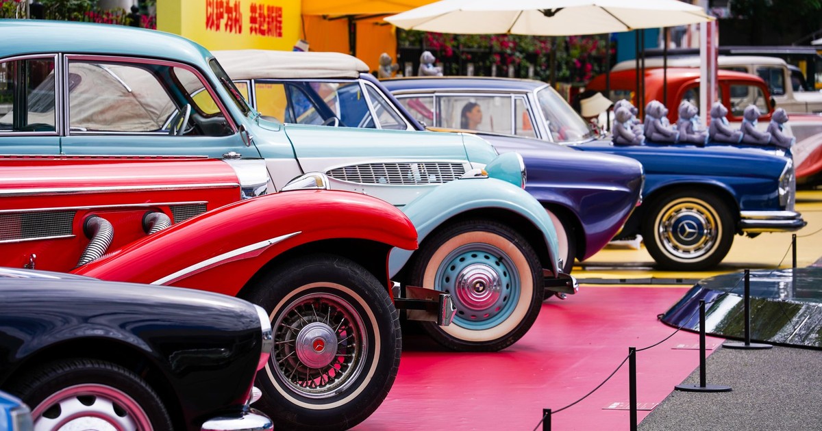 A row of colorful vintage cars showcased at an outdoor auto exhibition.