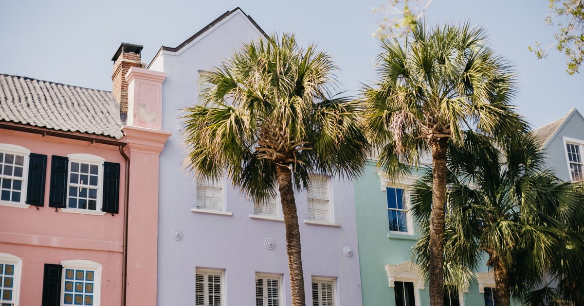 Vibrant pastel homes and palm trees on a sunny street in Charleston.