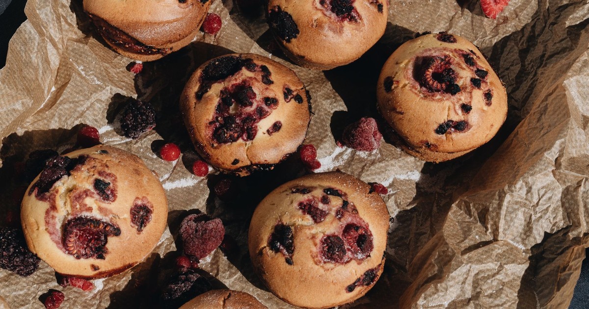 Freshly baked berry muffins with strawberries and currants on crumpled paper.