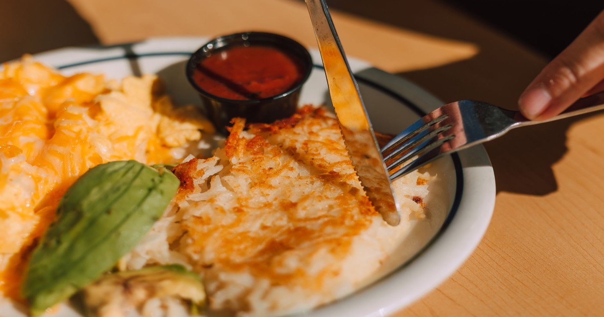 Tasty breakfast with hash browns, scrambled eggs, and avocado served on a sunny morning.